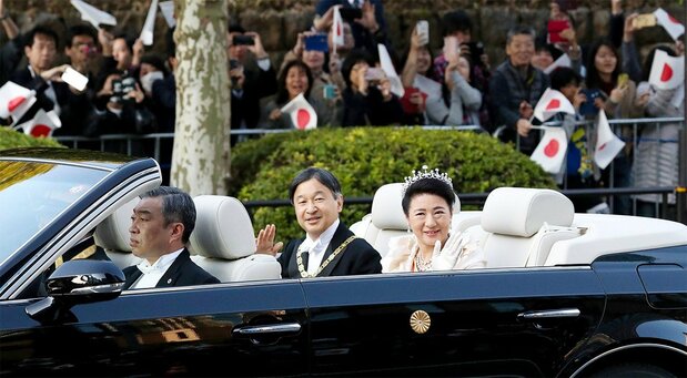 Spectators wave as the imperial couple passes in a convertible during the imperial procession in Tokyo on November 10, 2019. (© Jiji)