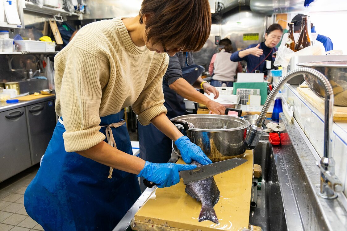 Сотрудники магазина морепродуктов Sakanaya Marukama в районе Китакамакура чистят и разделывают рыбу для покупателей (© Nippon.com)