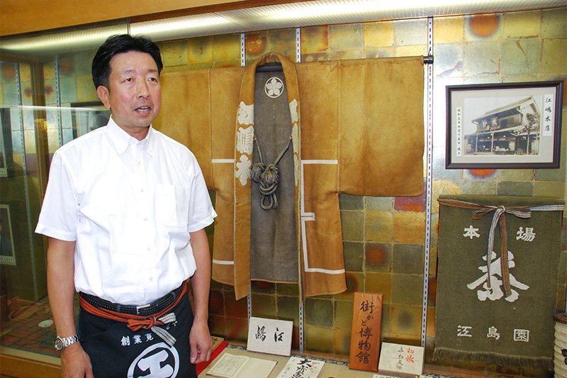 店内の展示コーナーを前に、「江嶋」の350年余の歴史について説明する江島賢17代当主