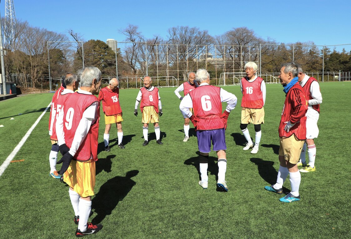 Los jugadores del Red Star se preparan para su partido. El color de sus pantalones indica la edad. El morado indica que un jugador tiene 85 años o más. (© Amano Hisaki)