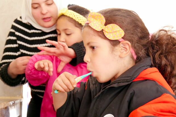 Children brushing their teeth after lunch. This activity is part of overall guidance to promote good hygiene. More children are now participating voluntarily.