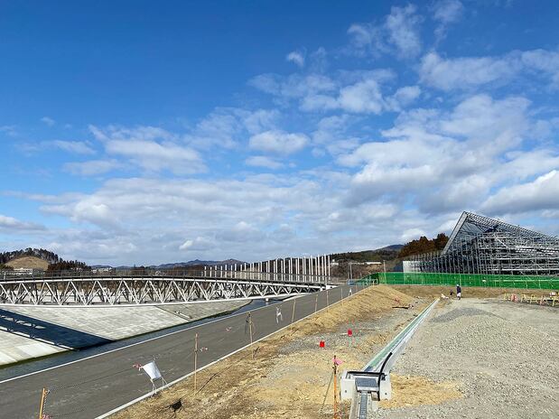 震災後、旧市街地は約10メートルかさ上げされ、中橋も架け替えられた。右後方に見えるのは、建築家・隈研吾さんが設計した震災伝承施設「南三陸311メモリアル」の工事現場
