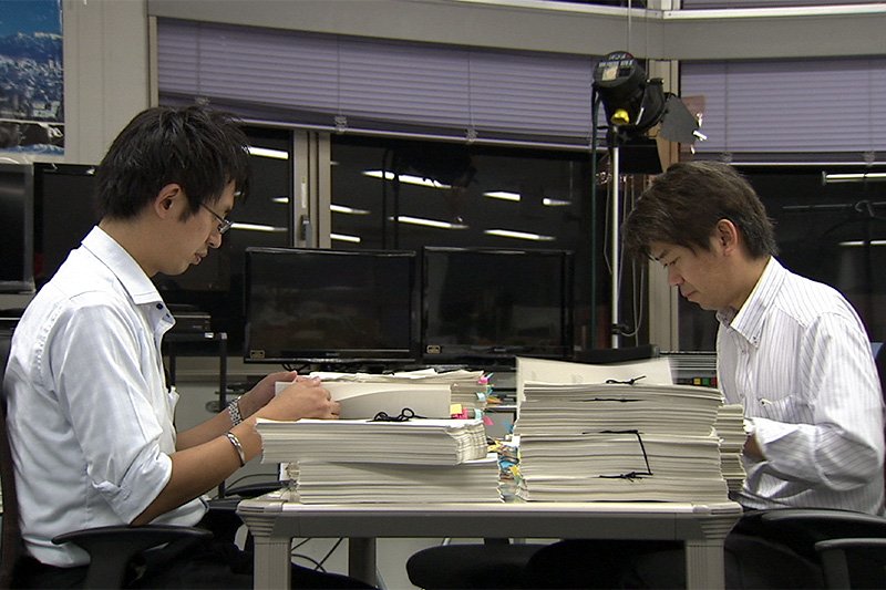 Sunazawa (left) and Miyagi tackle the piles of reimbursement records. (Courtesy of Tulip TV.)