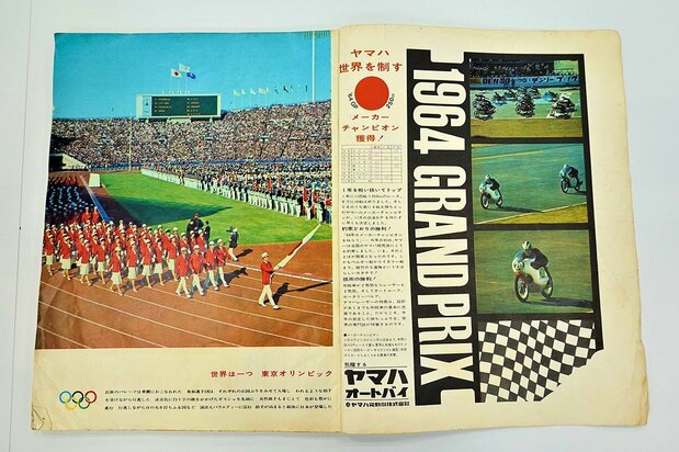 秋晴れの下、旗手の福井誠(ローマ五輪競泳銀メダリスト)を先頭に入場行進をする日本選手団。広告ページには、ヤマハ発動機(現・ヤマハ)が二輪グランプリで初めて世界王座を獲得したニュースが躍る。
