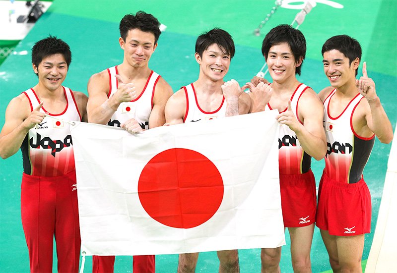 日本队在男子体操团体赛中夺冠，选手们手拿日本国旗摆造型。从左至右依次为山室光史、田中佑典、内村航平、加藤凌平、白井健三（8月8日）