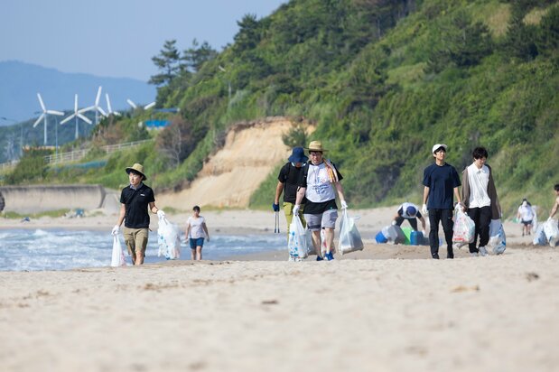在烈日下走在软塌塌的沙滩上,运送大量的垃圾是一件力气活