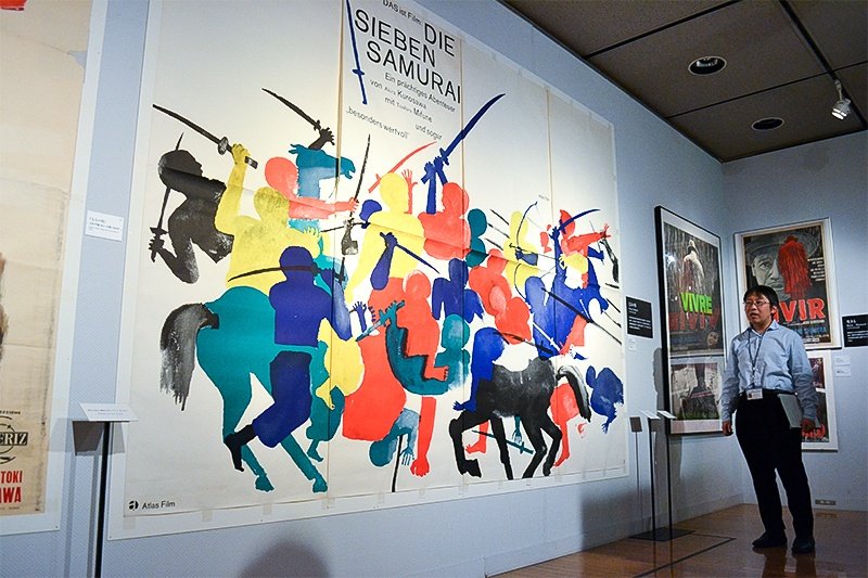 M. Okada devant l’affiche ouest-allemande des Sept Samouraïs de Hans Hillmann de 1962.