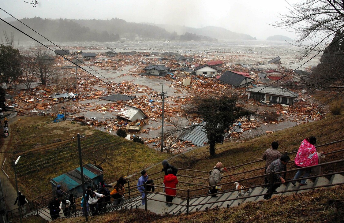 3月11日 下午3时37分 宫城县南三陆町志津川在高地上避难的居民，茫然地观望着一瞬间面目全非的村景。