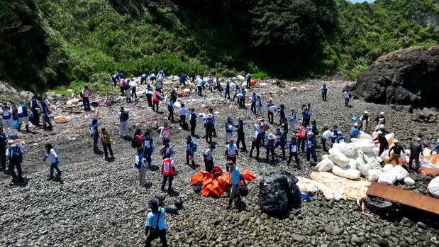石だらけで足場の悪い海岸を人海戦術で清掃していく 写真:日本財団