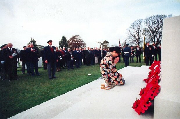 英国の「戦没者追悼の日」にケンブリッジの墓地で行われた追悼式に参列して、祈りを捧げる小菅信子さん。この写真が地元紙の1面に「友情の涙――式典に繰り広げられた感動の光景」の見出し付きで掲載された。(1996年11月、小菅さん提供)