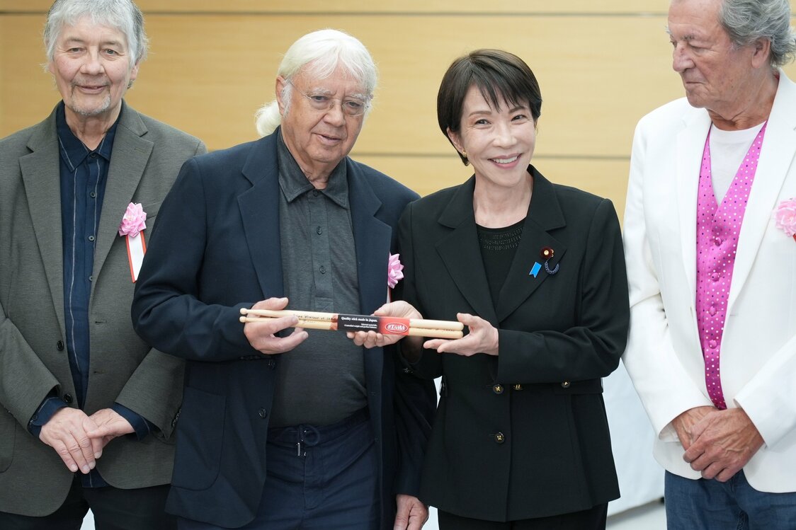 ドラムのイアン・ペイスさん（左から2人目）にドラムスティックを贈る高市早苗首相（時事）