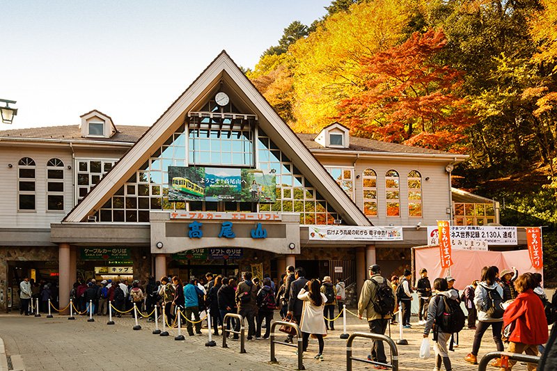 高尾登山电铁公司的登山缆车和空中索道的乘车处，从高尾山口站步行5分钟可达。乘坐缆车从“清滝站”到“高尾山站”（海拔472米），单程耗时6分钟。乘空中索道从“山麓站”到“山上站”（海拔462米），单程耗时12分钟