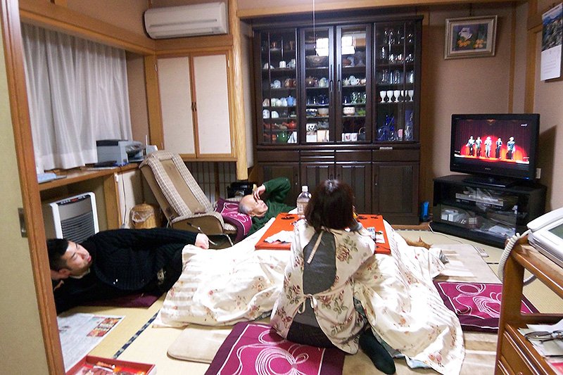 Une famille regardant la télévision autour du kotatsu.