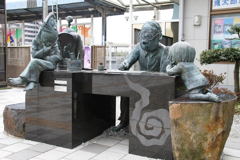 Una estatua frente a la estación de Sakaiminato muestra a Mizuki Shigeru dibujando, rodeado de los personajes creados por él.