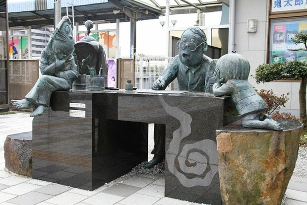 Ces statues à la sortie de la gare de Sakaiminato représentent Mizuki Shigeru au travail, entouré de certaines de ses créations. (Nippon.com)