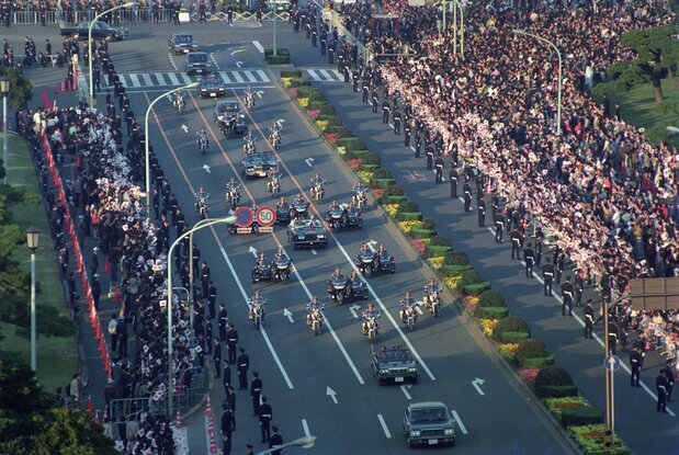 平成の「祝賀御列の儀」で沿道を埋めた人たちの中を進む天皇皇后両陛下の車列=1990年11月12日、東京・千代田区の内堀通り祝田橋交差点(読売新聞社/アフロ)