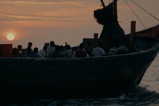 Fotograma de Lost Land. Unos refugiados, muchos más de los que en realidad caben, se suben a un destartalado barco pesquero para embarcarse en una peligrosa travesía de varios días. (©2025 E.x.N K.K.)