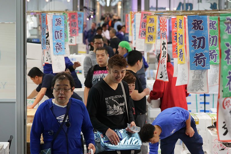 Le marché de semi-gros des produits de la mer du marché de Toyosu pris d’assaut le jour de l’ouverture. Tous les stands sont ornés d’affiches célébrant les premières livraisons.