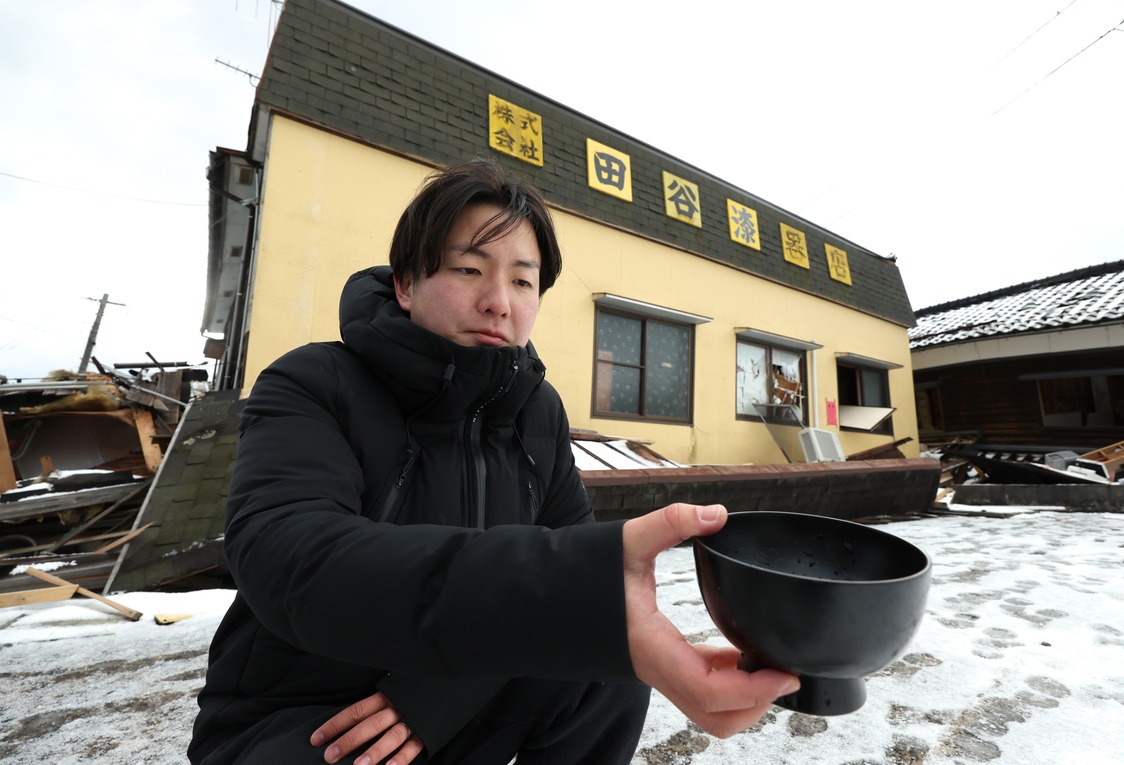 Taya Takahiro sostiene un cuenco lacado hallado en un taller de Wajima cuya planta baja había quedado destrozada. El 16 de enero de 2024. (© Jiji)