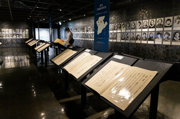 生存者の証言が並ぶ第四展示室。壁には、沖縄戦で命を落とした生徒と教師の写真が