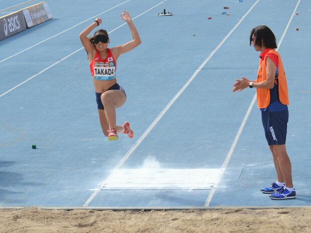 2019年11月9日、世界パラ陸上の女子走り幅跳び(視覚障害T11)で、大森盛一コーチ(右)の声と手拍子を頼りに跳躍する高田千明(ほけんの窓口)=アラブ首長国連邦・ドバイ(時事)