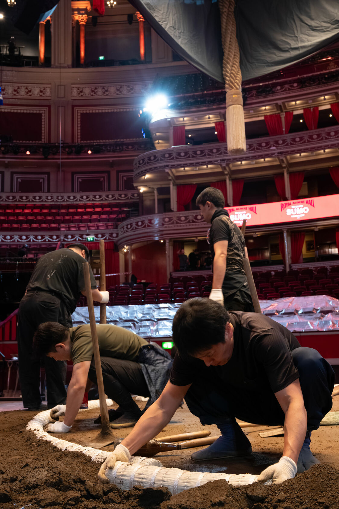 Workers lay down the plastic tawara bales marking the edge of the ring. (© Tony McNicol)