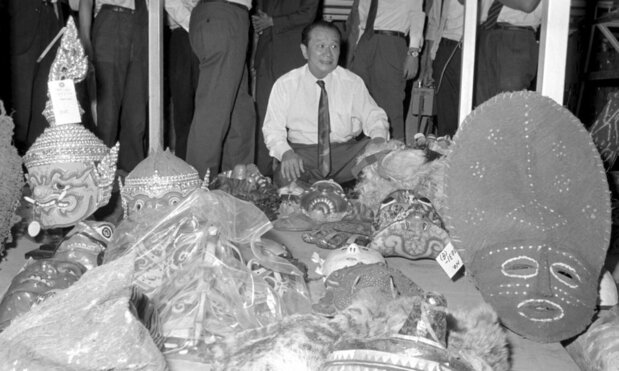 أوكاموتو تارو في 4 سبتمبر/ أيلول 1969، محاطًا بالأقنعة وغيرها من الفنون الشعبية التي تم جمعها لعرضها في معرض أوساكا عام 1970. (© كيودو)