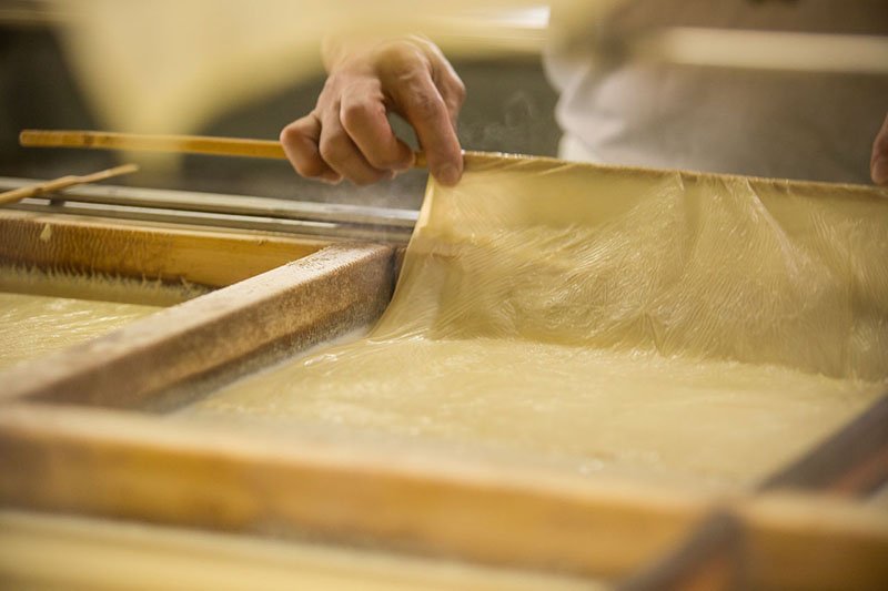 Un artesano con años de experiencia se encarga de extraer la piel o nata de tofu.
