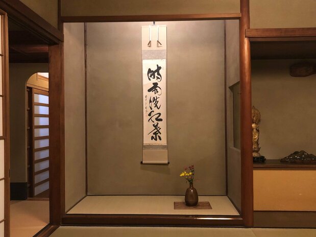 A flower arrangement and hanging scroll decorate a tokonoma.