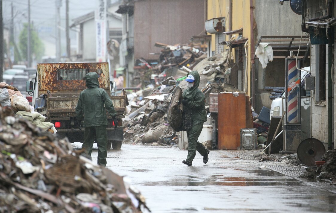 球磨川氾濫で浸水した住宅地の片づけをするボランティアたち、人吉市にて（時事通信）