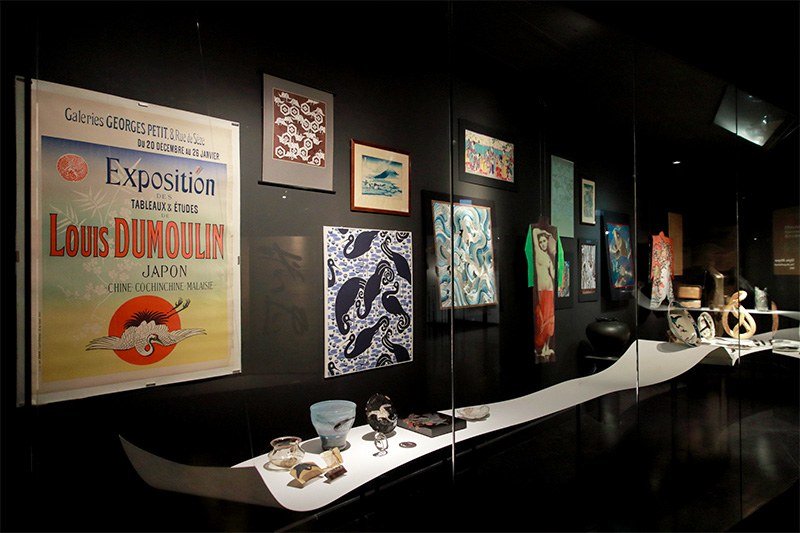 左端のポスターはフランスの画家ルイ・デュムーラン（1860-1924）が日本への旅行でインスピレーションを受けた絵画の展覧会（1889年）のもの。丹頂鶴のモチーフが、前に置かれた皿〈尾形乾山（1663-1743）の作とされる〉に描かれたような日本的な絵柄から「借用」されたのが一目瞭然だ