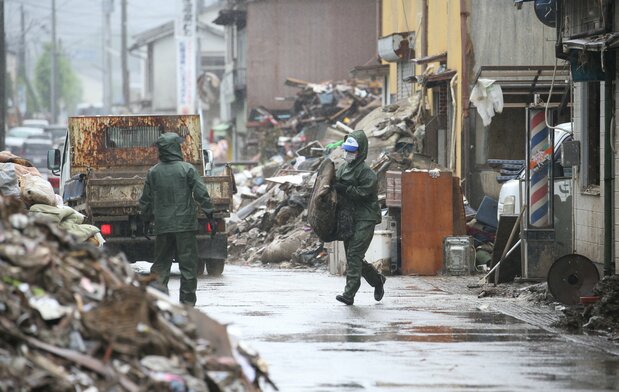 球磨川氾濫で浸水した住宅地の片づけをするボランティアたち、人吉市にて(時事通信)