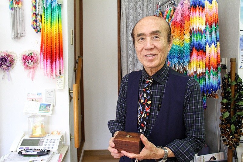 佐々木雅弘さんが営む理容室の壁には、全国から送られてくる千羽鶴が飾ってある。ネクタイも折り鶴模様。（撮影＝土井 恵美子）