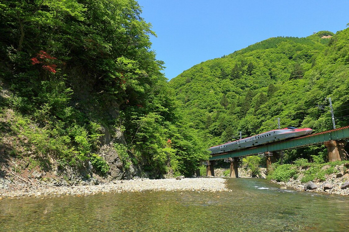 «Комати» – скоростной поезд серии Е6 линии Акита синкансэн, следующий по маршруту линии японских железных дорог JR Тадзавако-сэн Акабути-Тадзавако (поселок Сидзукуиси, префектура Иватэ, город Сэнбоку, префектура Акита). Июнь. Поезда синкансэн двигаются на высокой скорости, связывая города друг с другом. Однако линии Акита синкансэн и Ямагата синкансэн уходят с магистральных линий и далее следуют по переделанным на стандартные 1435-миллиметровые линии Ооу-хонсэн и Тадзавако-сэн. Поезд синкансэна, бегущий через горные районы, покрытые зеленью, представляет собой исключительное зрелище