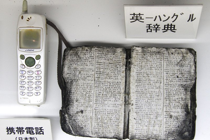 工作船引き揚げで回収された日本製の携帯電話と英・ハングル辞典