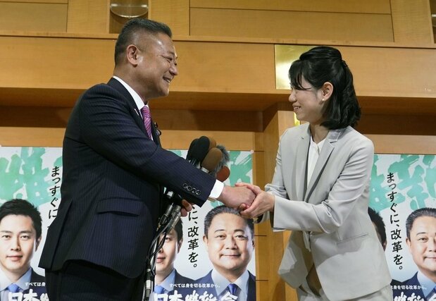 衆院和歌山1区の補欠選挙で初当選を決め、日本維新の会の馬場代表(左)と握手する林佑美氏=4月23日深夜、和歌山市(共同)