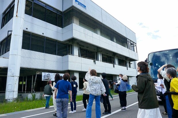 Varias participantes observan la marca de la altura que alcanzó el tsunami en un edificio en el que se salvaron 327 personas. (Fotografía de la autora)