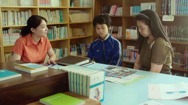 La madre de Kanto (Shimokura Emi, a la derecha), atónita cuando su hijo (Shimokura Mikito) dice por primera vez que quiere salir del pueblo, durante una entrevista con una profesora de su escuela ©AINU MOSIR LLC/Booster Project