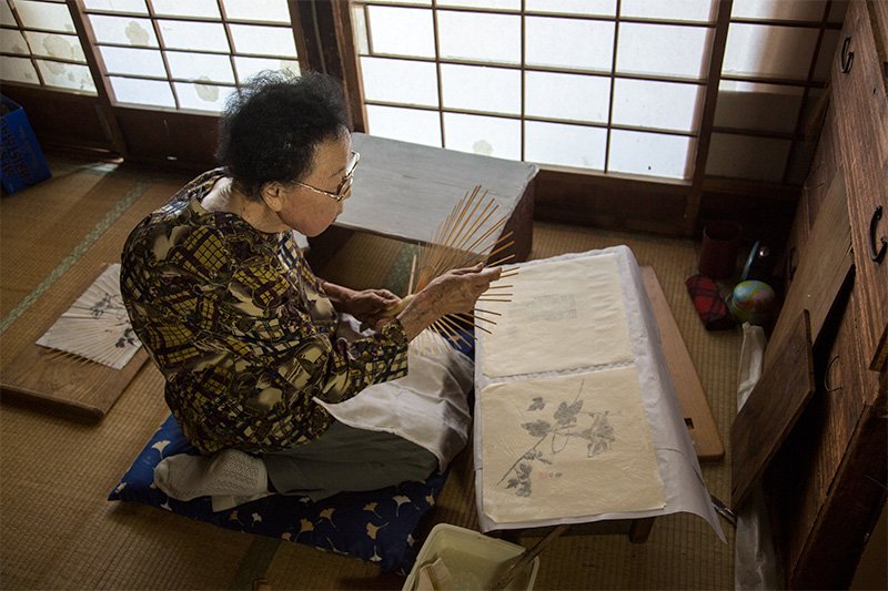 骨作りからすべて一人の手仕事。朝顔の絵柄の手漉き和紙を貼る。団扇作り80年余の圷總子さん