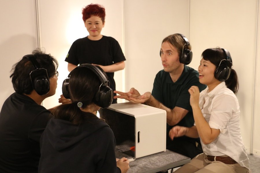 A nonhearing guide watches on as event participants take on the challenge of describing objects to one another without voiced words to help.
