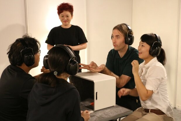 A nonbearing guide watches on as event participants take on the challenge of describing objects to one another without voiced words to help.