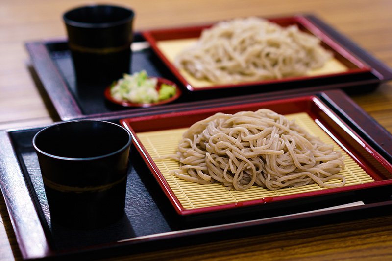 En premier plan, un plat de akasoba, avec teinte est légèrement pourprée. En second plan, les shirosoba, un plat de soba classiques.