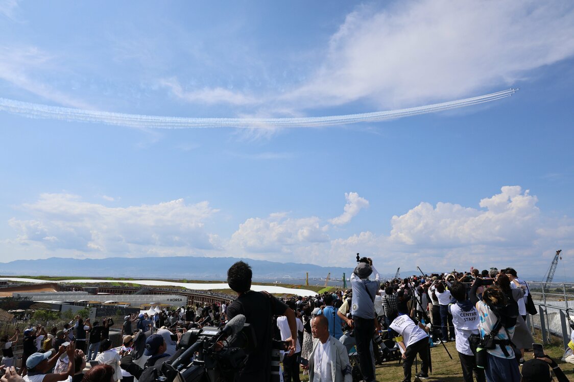 Des spectateurs admirant les performances des avions Blue Impulse au-dessus du site de l’Expo universelle d’Osaka 2025, le 12 juillet 2025. (Jiji)