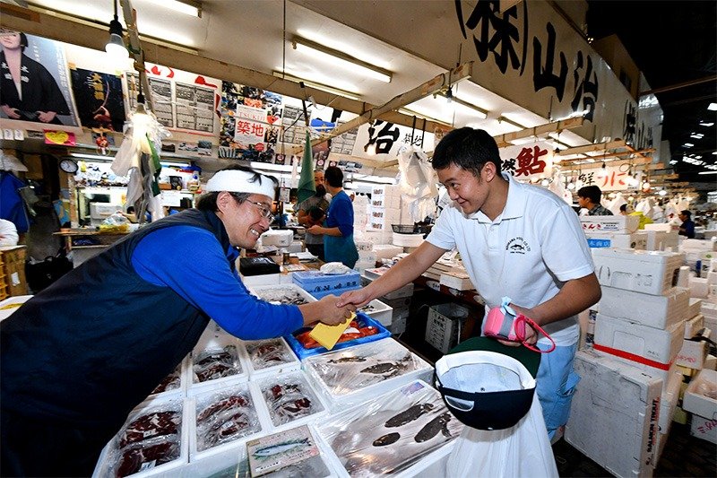 最終営業日を迎えた築地市場の水産仲卸売場で、握手する仲卸業者と買い出し人＝2018年10月6日、東京都中央区［代表撮影］（時事）