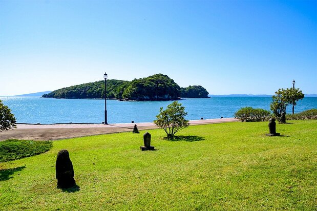 La isla Koiji, en la bahía de Minamata. En la orilla hay monumentos de piedra en memoria de las víctimas de la enfermedad de Minamata. La ciudad cuenta con un museo dedicado al desastre provocado por la contaminación con mercurio que conmocionó al mundo en las décadas de 1950 y 1960. La costa ofrece hermosos paisajes y zonas de aguas termales. (© Pixta)