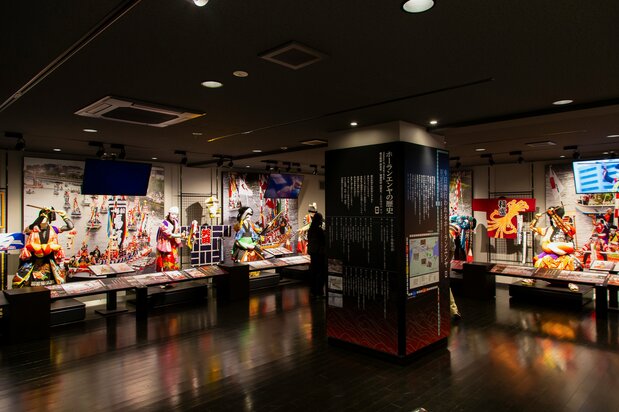 Sala de exposiciones, con muñecos de tamaño real a imagen y semejanza de los kengai y los zaifuri de las Cinco Grandes Tierras.