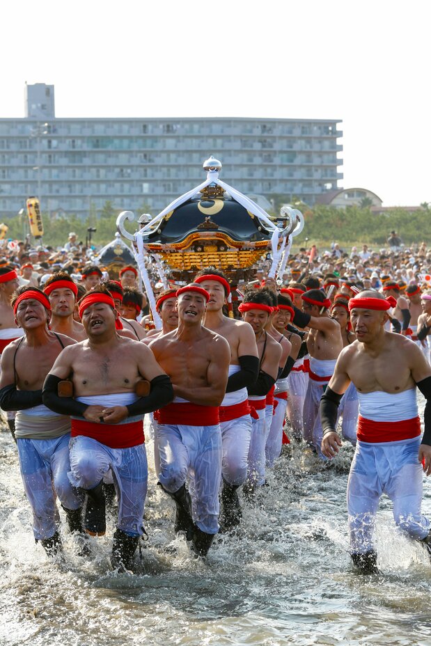 The sea churns with hundreds of men carrying mikoshi. (© Haga Library)