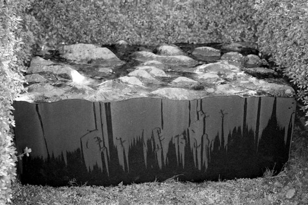 Karōji Kentarō’s grave at the foot of Mount Hakodate in a photograph taken after rain. Sculpted by Akiyama Yūtokutaishi, the gravestone evokes the waves of the Sea of Okhotsk.