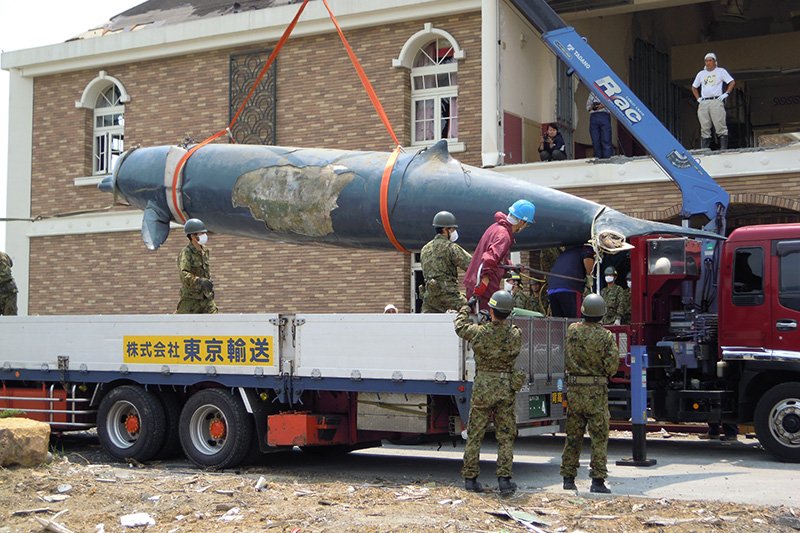 Uniformed SDF personnel assist with the move of the beaked whale taxidermy specimen. Almost 10 meters long, it is the largest such exhibit in Japan.