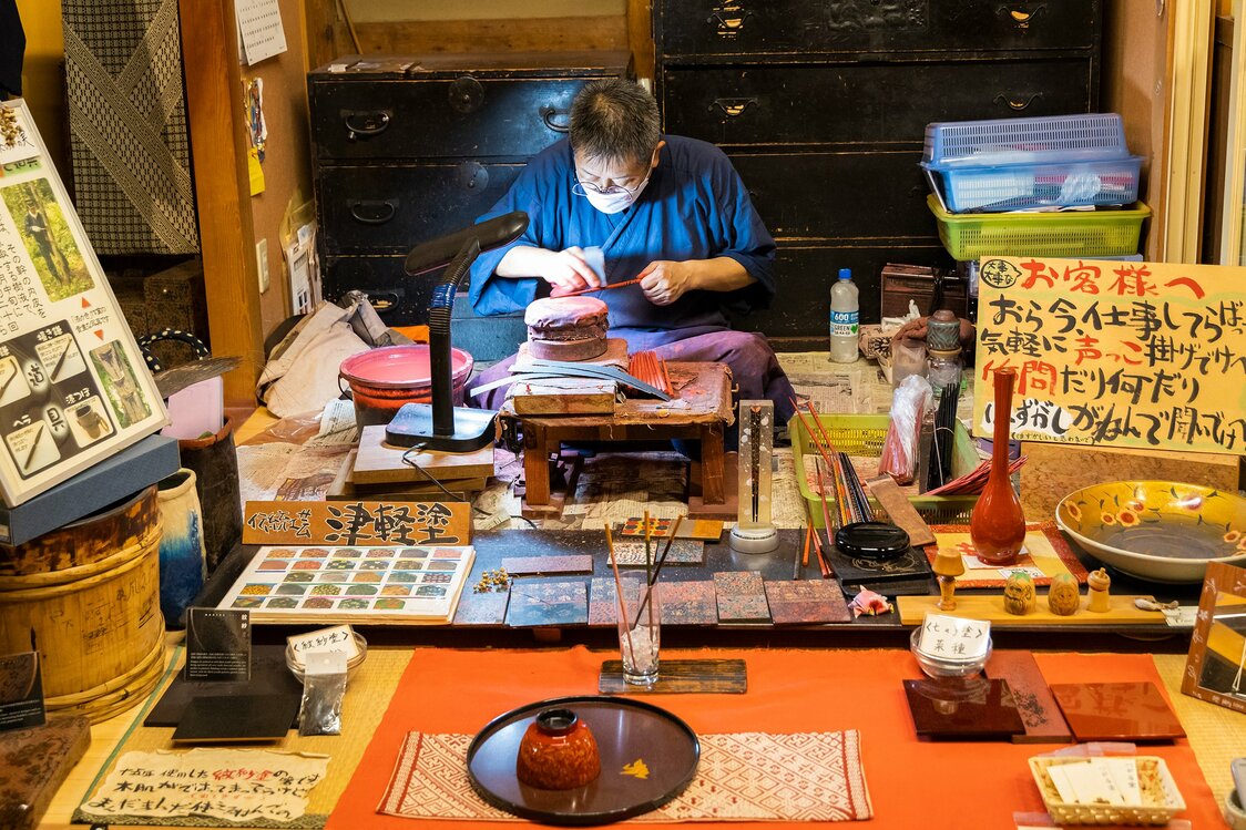 漆を塗っては研ぎ、模様を浮き上がらせる津軽塗の作業風景。職人さんに声を掛けると、質問などに答えてくれる